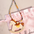 Équestre Leather Handbag Charm featuring a leather rocking horse design with colorful fabric strap on pink satin pouch.